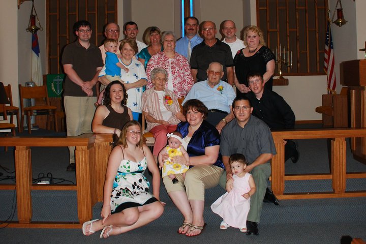 Elizabeth and Wilfred Schoen surrounded by family at their 65th wedding anniversary, seated at the center of a large group in a church