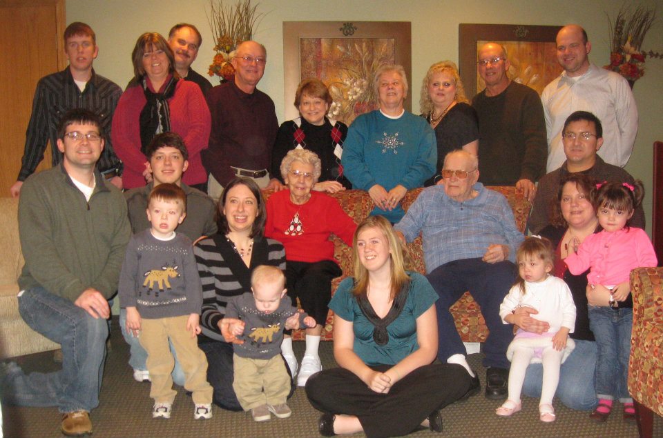 Elizabeth and Wilfred Schoen seated on a couch surrounded by their children, grandchildren, and great-grandchildren
